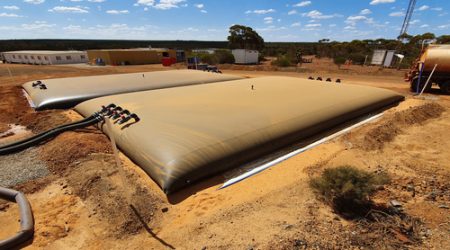 Two flexible water bladders filled with water on a remote mine site