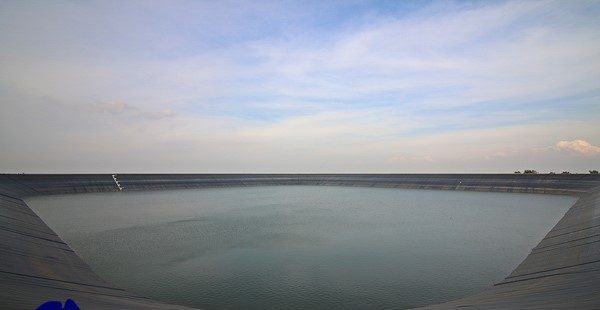 Large lined dam filled with potable water on a day with a cloudy sky